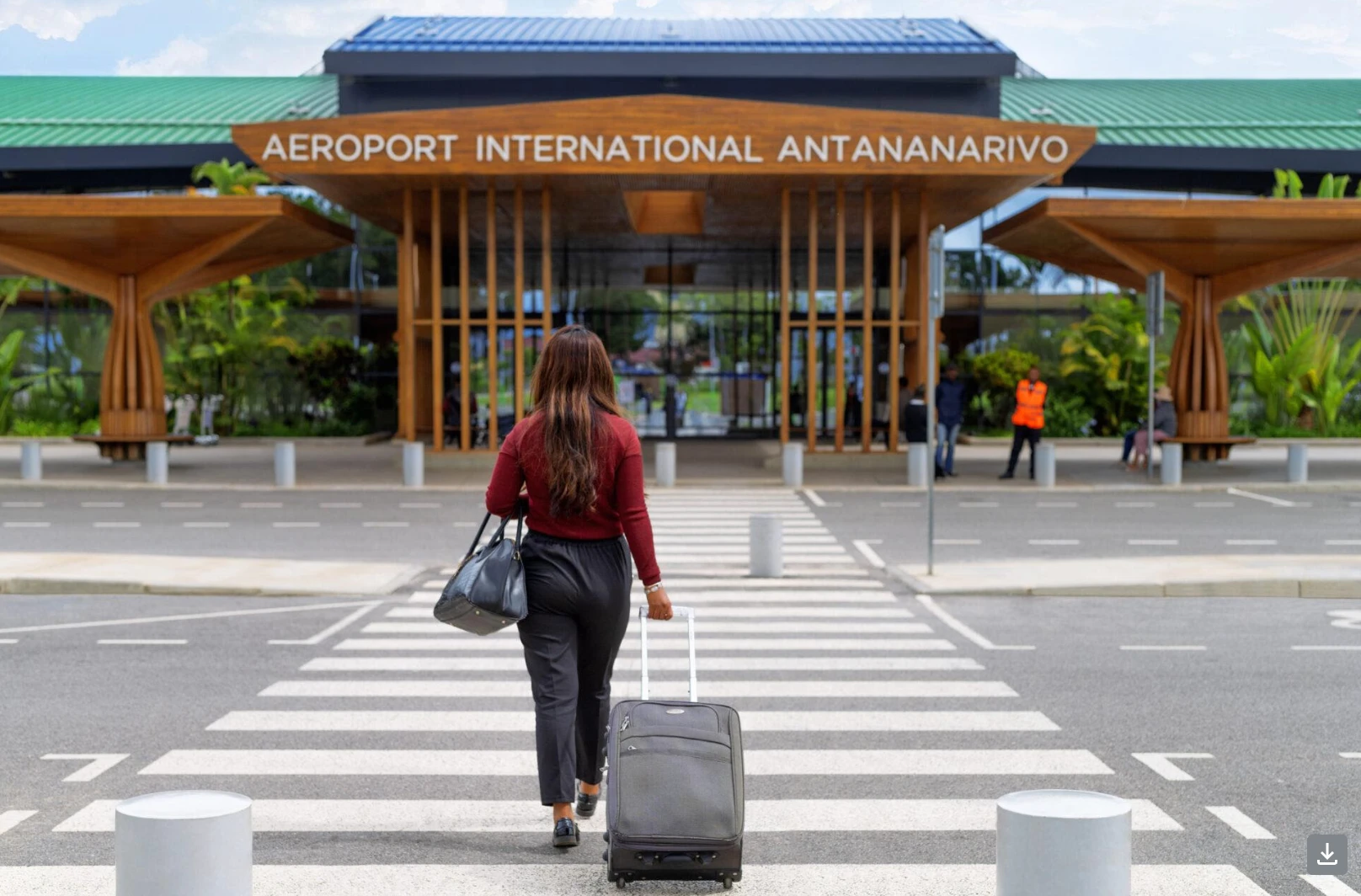 Voyageuse tirant sa valise vers l'entrée de l'aéroport international d'Antananarivo